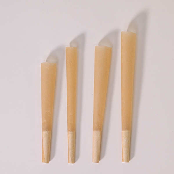 four unrefined brown pre-rolled cones lying on a white background