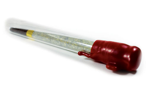 A glass joint tube with a red wax coating keeping it closed. The pre-roll inside has a black filter and gold cigar band
