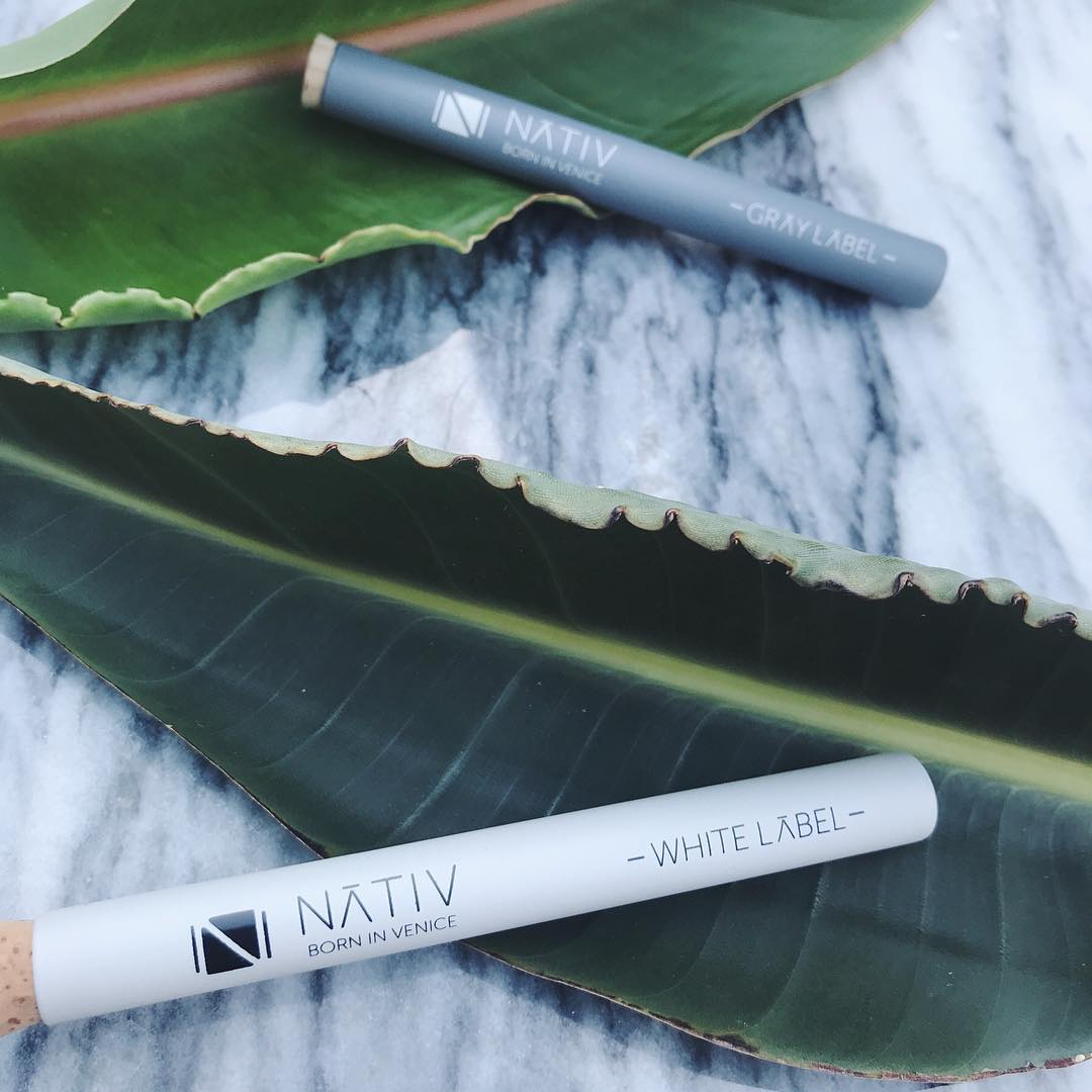 A Nativ branded white tube with a cork top on top of a succulent leaf