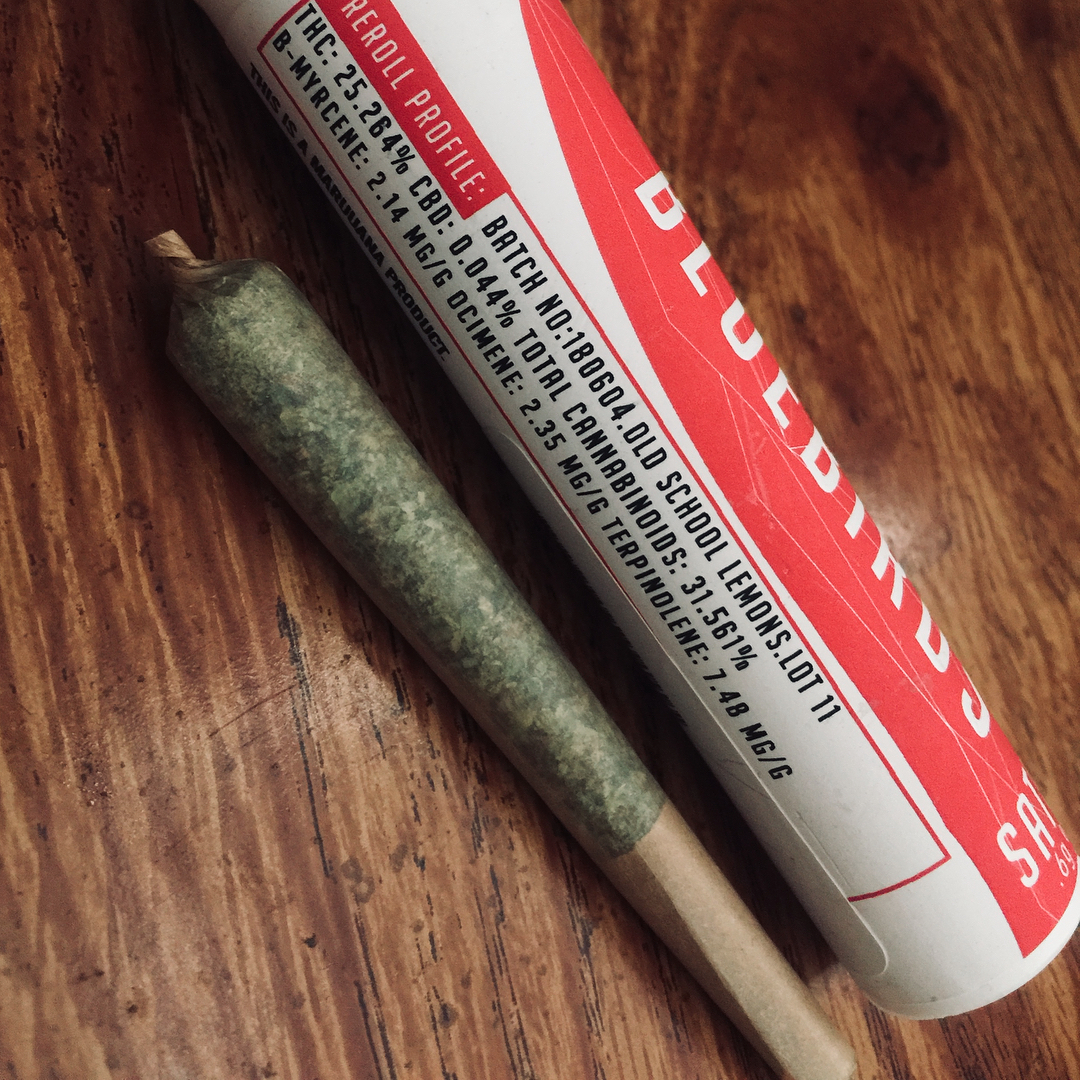 a pre-roll with an unbranded filter tip lying next to a package with the branding facing away from the camera